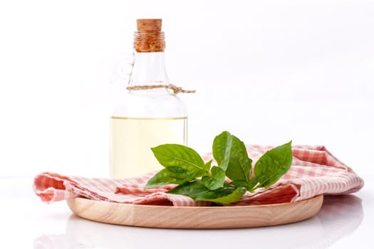 Branch of fresh  basil in wooden plate with olive oil on cutting board isolate on white background.