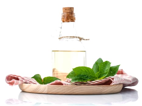 Branch of fresh  basil in wooden plate with olive oil on cutting board isolate on white background.