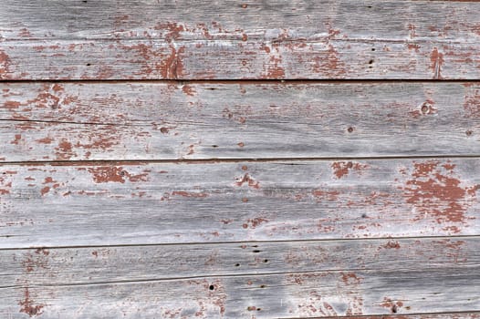 The red paint that once covered these planks is now faded and peeled.