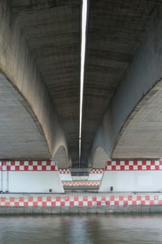 Under the bridge with the river.