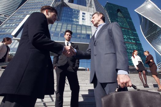 Business people shaking hands, finishing up a meeting outside office