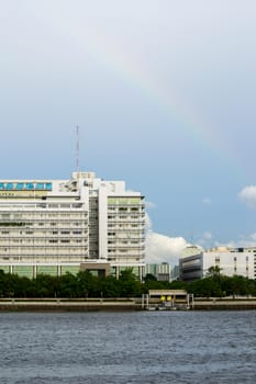 Riverside buildings with blue sky and rainbow