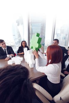 Businesspeople at meeting in office holding jigsaw puzzle