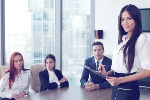Business woman with folder and her colleagues at meeting in office