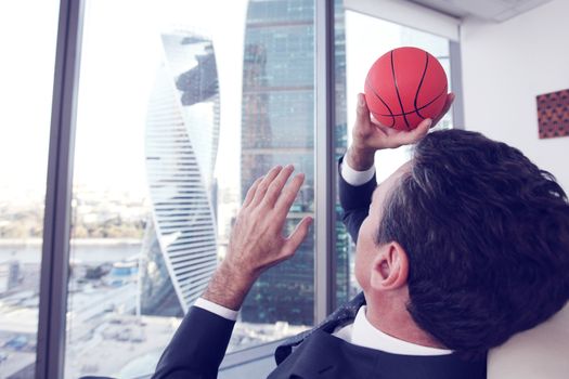 Business man playing with a basketball at the office