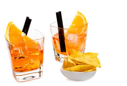 two glasses of spritz aperitif aperol cocktail with orange slices and ice cubes near tacos chips on white background