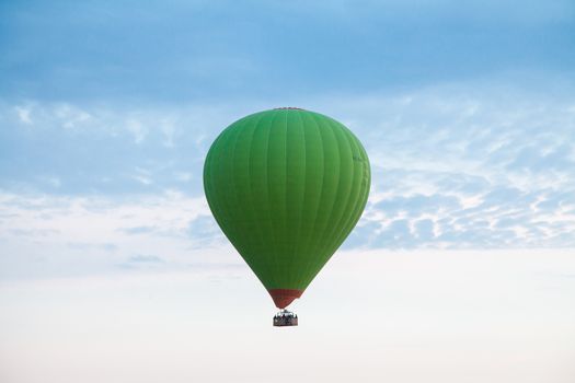 Green hot air balloon travelling up in the air