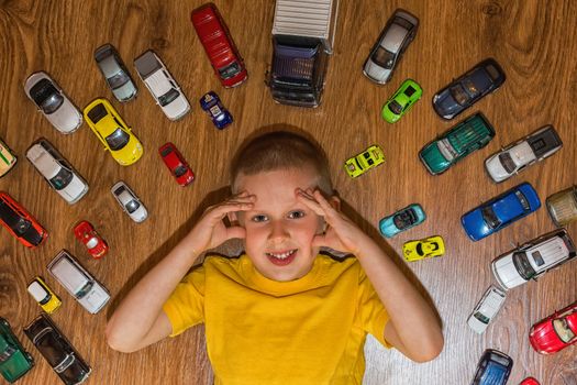 The photograph depicts a young boy with toy cars