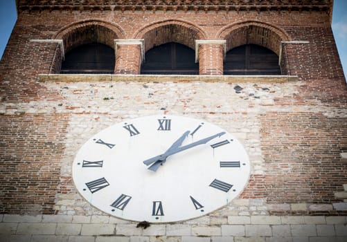 big white clock on the facade of the bell tower of a Romanesque abbey