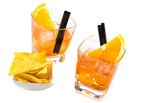 top of view of two glasses of spritz aperitif aperol cocktail with orange slices and ice cubes near tacos chips on white table background