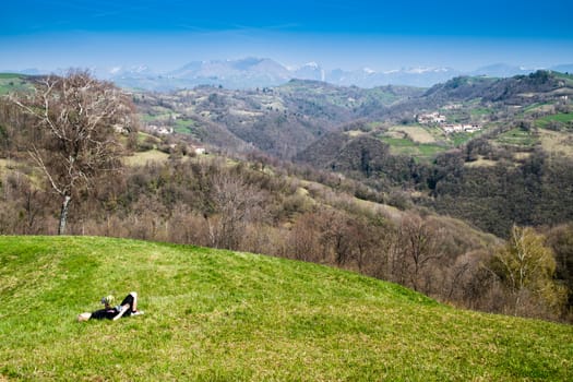 young woman lying on a green meadow with a bouquet of wild flowers freshly picked