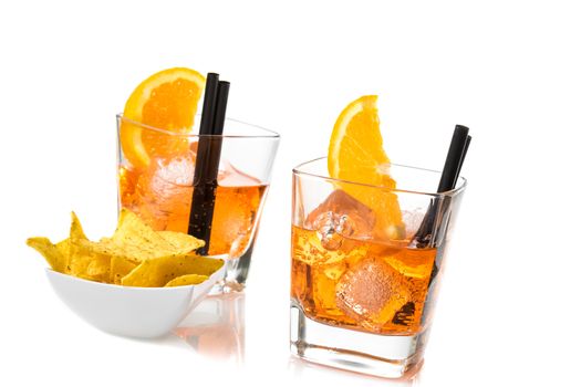 two glasses of spritz aperitif aperol cocktail with orange slices and ice cubes near tacos chips on white background