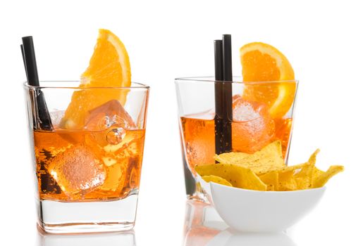 glasses of spritz aperitif aperol cocktail with orange slices and ice cubes near tacos chips on white table background