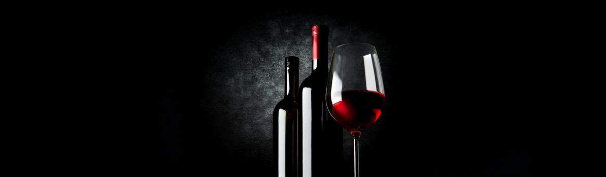 Two bottles and wineglass on a black background
