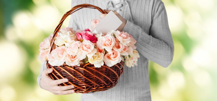 holidays, people, feelings and greetings concept - close up of man holding basket full of flowers and postcard over green background