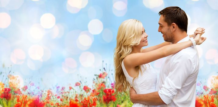 summer holidays, people, love and dating concept - happy couple hugging over blue sky lights and poppy field background