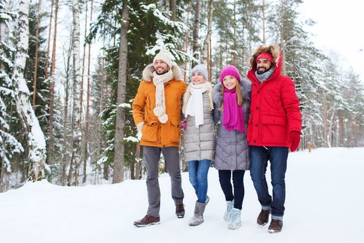 love, relationship, season, friendship and people concept - group of smiling men and women walking in winter forest