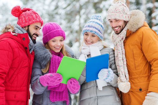 technology, season, friendship and people concept - group of smiling men and women with tablet pc computers in winter forest