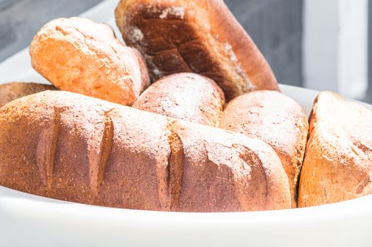 Various types of bread in a large white bowl.