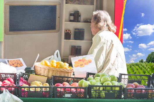 Mature woman shopping for a simple sales booth on a street outside the city.