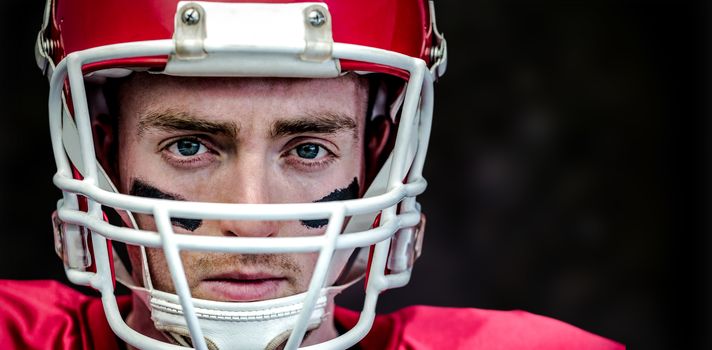 Portrait of focused american football player wearing his helmet against black background