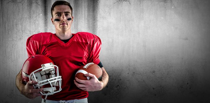 American football player holding helmet against grey background