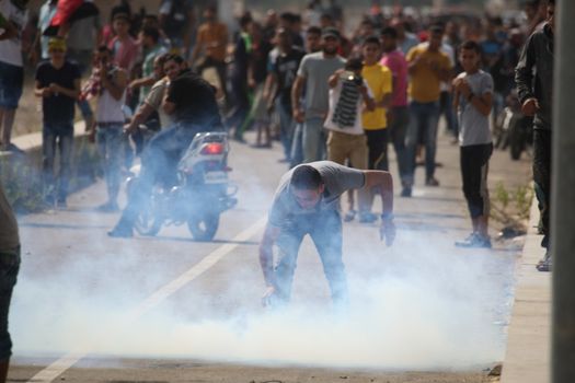 PALESTINE, Gaza Strip: A man grabs a can of tear gas near the Erez border crossing between Israel and the Gaza Strip on October 13, 2015.As a wave of stabbings hit Jerusalem, violent protests flared up in the West Bank. The unrest has lead to warnings that a full-scale Palestinian uprising, or Intifada, could erupt. The unrest has also spread to the Gaza Strip, with fighting along the border in recent days leaving nine Palestinians dead. 