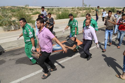 PALESTINE, Gaza Strip: A group of Palestinian protesters carry an injured man near the Erez border crossing between Israel and the Gaza Strip on October 13, 2015.As a wave of stabbings hit Jerusalem, violent protests flared up in the West Bank. The unrest has lead to warnings that a full-scale Palestinian uprising, or Intifada, could erupt. The unrest has also spread to the Gaza Strip, with fighting along the border in recent days leaving nine Palestinians dead. 