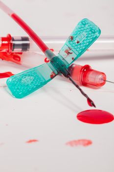 Concept Image - Surgical Aftermath Image of Needle Syringes and IV Lines Covered with Red Blood on White Background in Studio Still Life