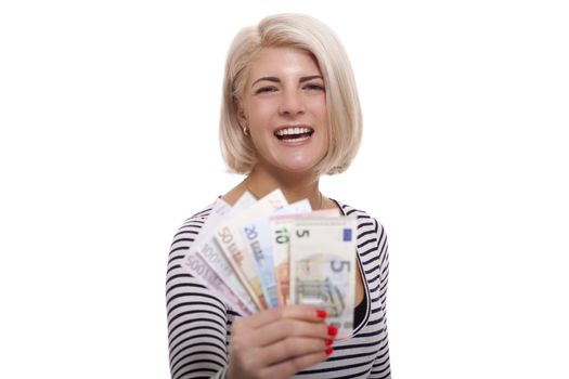 Attractive smiling blond woman holding up a handful of fanned Euro notes in different denominations, tilted angle conceptual image isolated on white