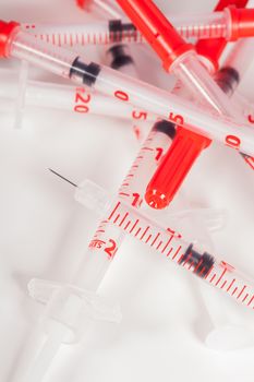 Still Life Close Up of Pile of Empty Syringe Needles with Red Safety Caps in Studio with White Background