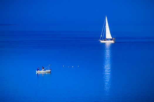 RAB, CROATIA - CIRCA AUGUST 2015: Small fishing boat and sailing boat meet in the blue sea.