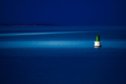 A buoy is reached at night by a patrol boat to be repaired.