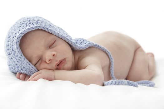 Sleeping newborn baby wearing a blue hat.