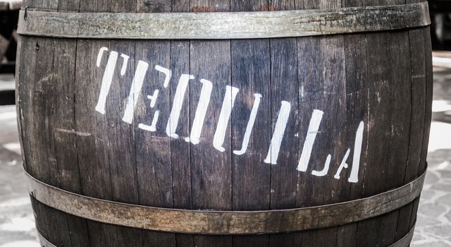 Wooden barrel with iron rings with the word "tequila" in white.