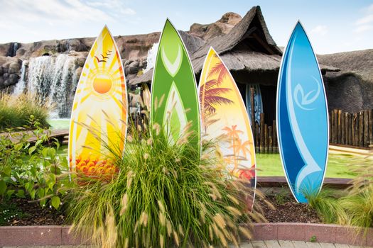 Colorful surfboards in front of a typical Hawaiian hut.