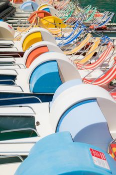 Funny row of colorful pedal boat parked on the lake.