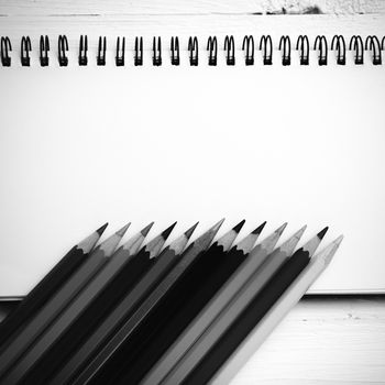 notepad with color pencil on white table view from above black and white color style