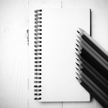 notepad with color pencil on white table view from above black and white color style