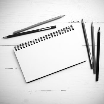 notepad with color pencil on white table view from above black and white color style