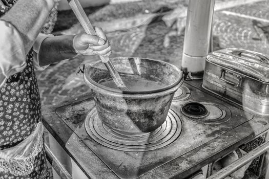 Cooking polenta in a copper pot on wood stove (dish of the Venetian tradition, Italy).