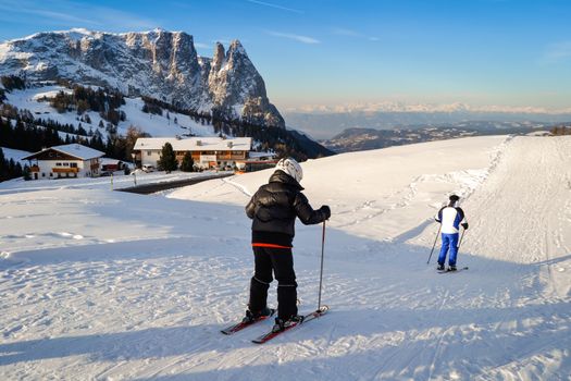 ORTISEI, ITALY - CIRCA DECEMBER 2012: Father and son skiing on the snowy slopes of the Alps.