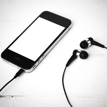 cellphone with earphone over white table black and white color tone style