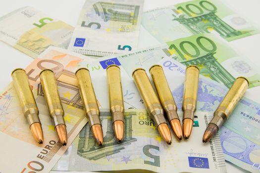 Composition with golden bullets and colorful banknotes.