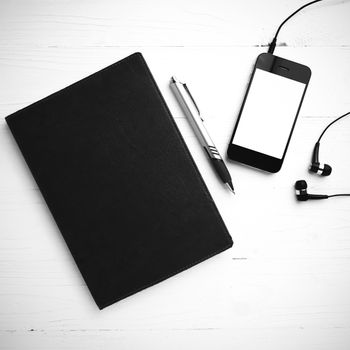 cellphone and notebook over white table black and white color tone style