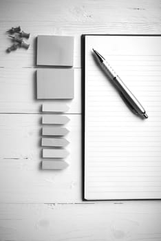 notepad with office supplies on white table view from above black and white tone color style