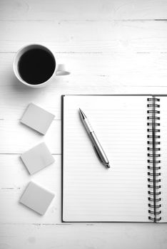 notepad and coffee cup on white table view from above black and white tone color style