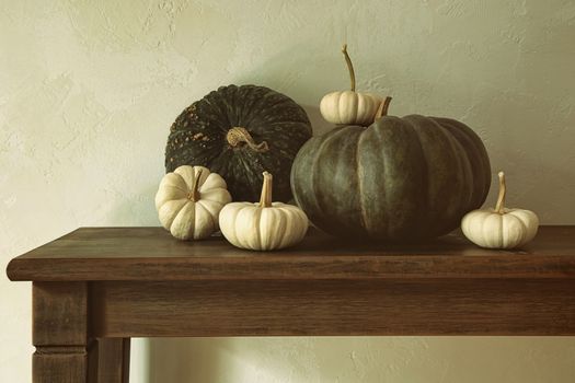Green pumpkins and small gourds on wooden table 