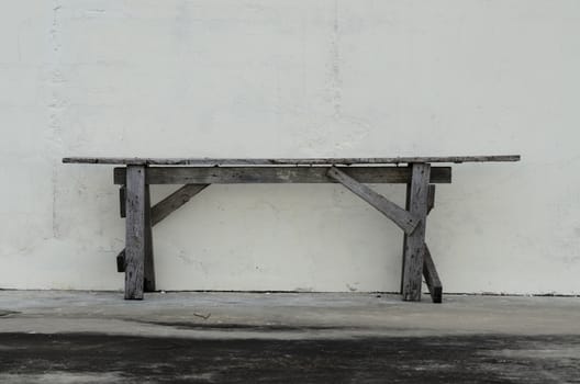 Single old chair in front of a white old wall.