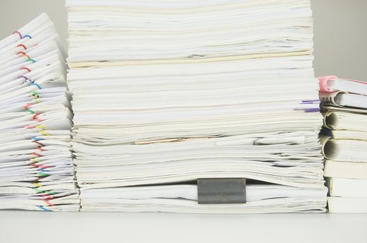 Paper of report and paperwork with books on table near wall.